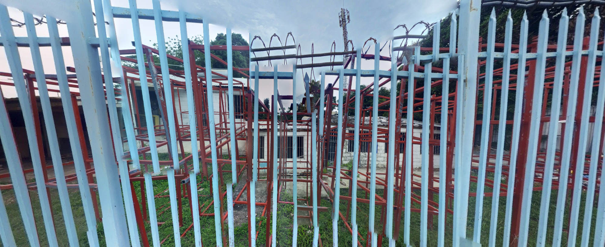 a photo into a yard, through a fence. the picture is a bit fractured, parts of it have been rearranged, so that the fence poles never quite align.