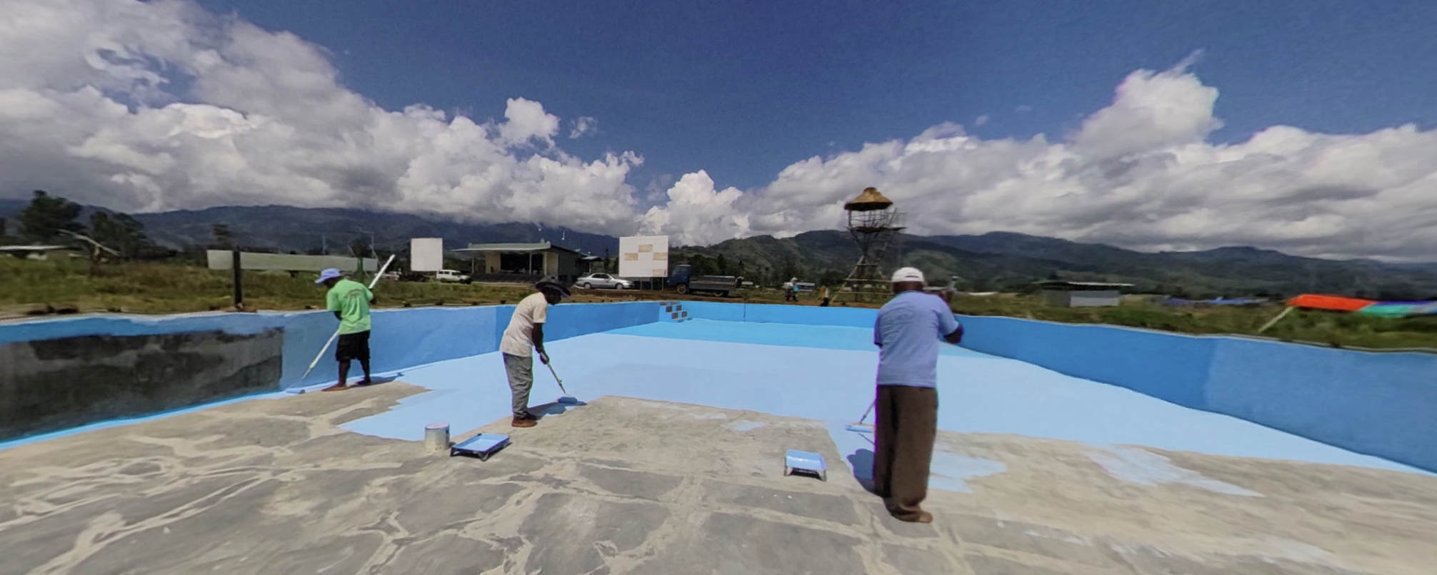 some people in a pit, painting it blue. maybe a swimming pool?